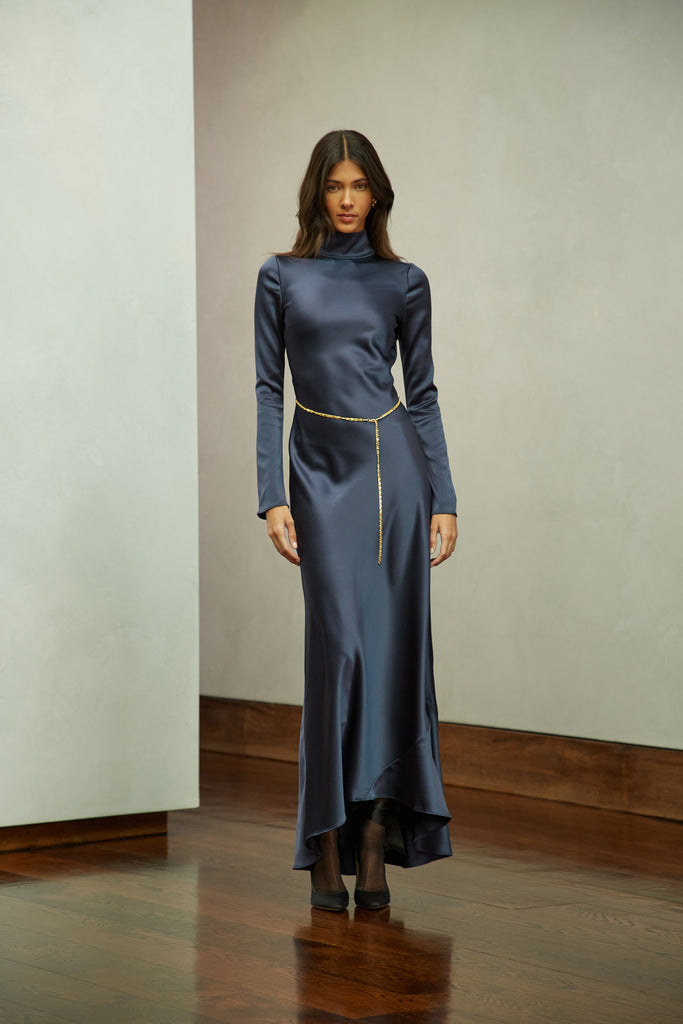 Navy Florence Dress This long sleeved satin gown is coveted for its fluid, liquid-like drape and movement. It is distinguished by a cowl turtleneck silhouette and plunging open back cutout. Includes 2 gold chain belts.Styling tip: Option to wear belt wrapped as a bracelet, or as a lariat cascading down the open back.