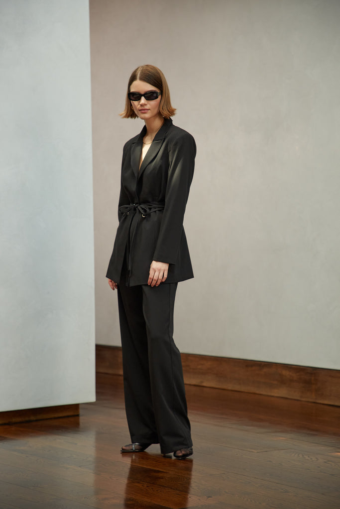 Black Rhodes Blazer This mid-length blazer features a detachable waist tie, allowing you to create a range of looks. The tailored single- breasted style features shoulder pads and front welt pockets. The Kat Trouser compliments the blazer perfectly.Style with The Kat Trouser