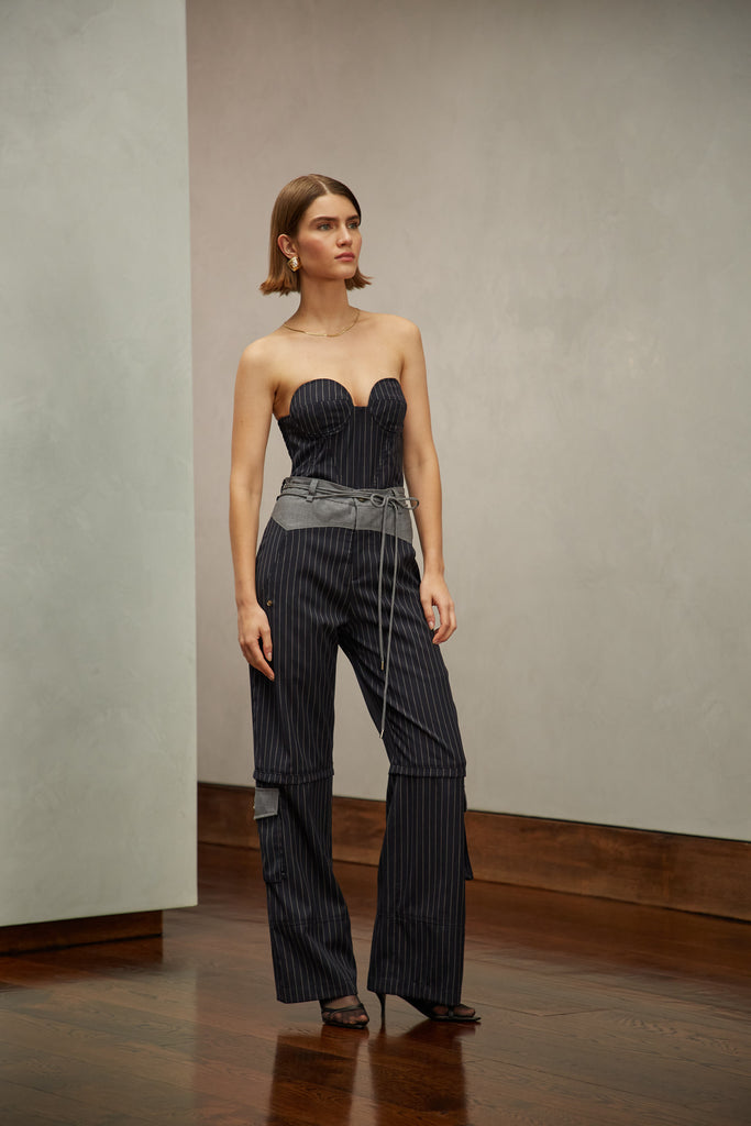 Navy Pinstripe Ronnie Trouser High-rise lightweight tailored trouser featuring contrasting waistband with self-fabric tie tunneled through two rows of belt loops. Featuring a relaxed leg fit with cargo style pockets and horn buttons. Ana is 5'9