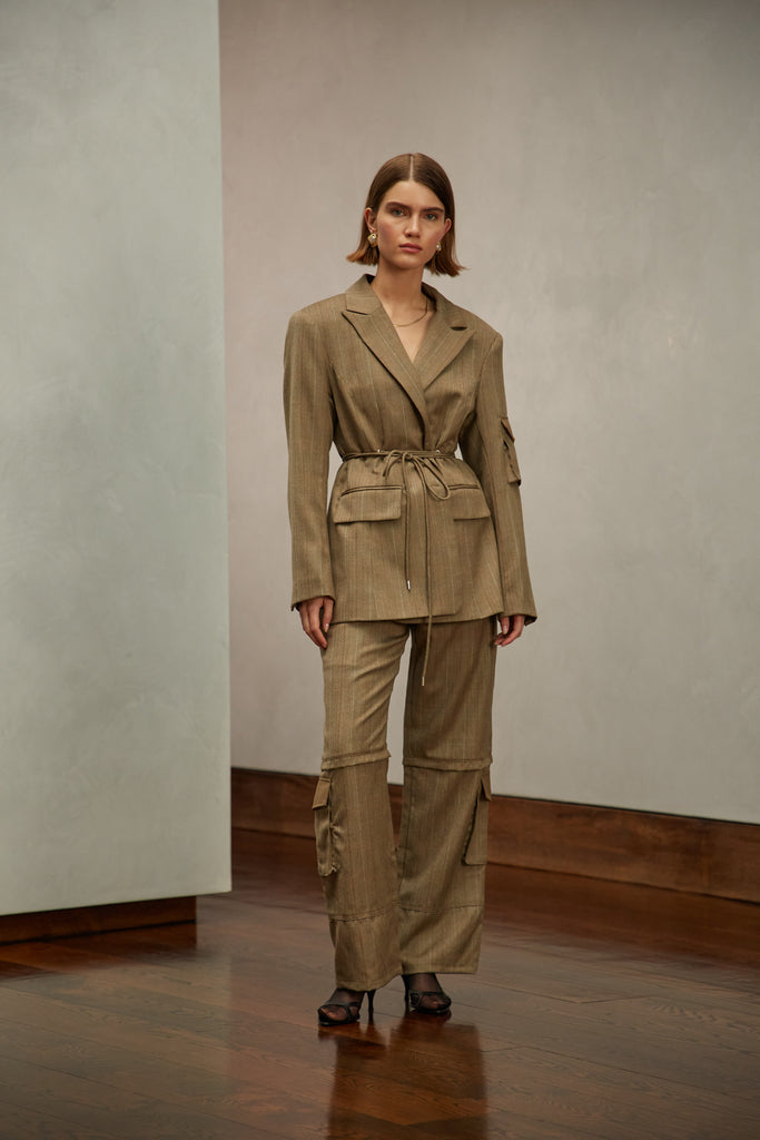 Camel Herringbone Ronnie Blazer Oversized 90's inspired blazer featuring a fixed self-fabric waist tie, cargo pocket detail on left sleeve, two standard flap pockets at hips, and custom selected horn buttons. Ana is 5'9