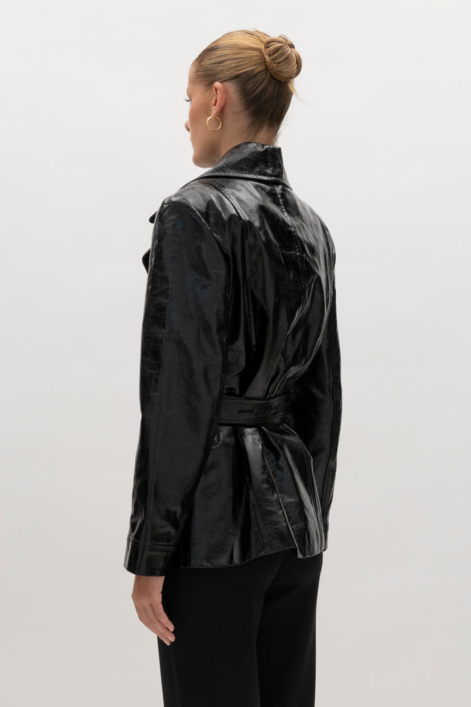 Black Kennedy Trench Crafted from 100% glazed cow leather, the Kennedy trench showcases sharp collars and clean lines. The cinched waist with buttoned belt offers a customizable fit.-100% glazed cow leather trench -Hidden stay button closure-Double wrap belt-Bracelet-length sleeve-On seam front pockets-Fully lined Handcrafted in small batches by our expert leather artisan in New York City.We recommend sizing up if a relaxed fit is desired otherwise choose your usual size.Styled with the Vivien LS Top & Mia Trouser