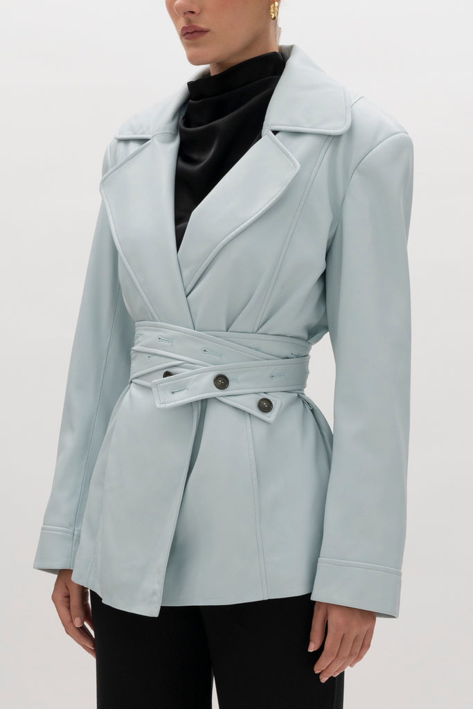 Powder Blue Kennedy Trench Handcrafted from soft vegan leather, the Kennedy trench showcases sharp collars and clean lines. The cinched waist with buttoned belt offers a customizable fit.-Hidden stay button closure-Double wrap belt-Bracelet-length sleeve-On seam front pockets-Fully lined Handcrafted in small batches by our expert leather artisan in New York City.We recommend sizing up if a relaxed fit is desired otherwise choose your usual size.Styled with the Vivien LS Top & Mia Trouser