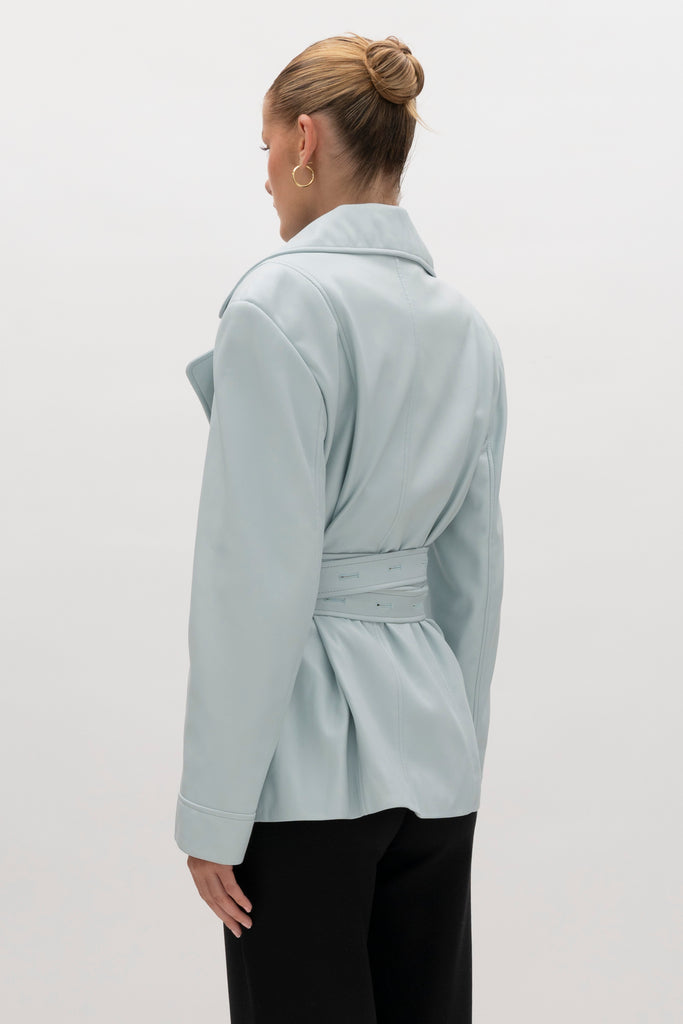 Powder Blue Kennedy Trench Handcrafted from soft vegan leather, the Kennedy trench showcases sharp collars and clean lines. The cinched waist with buttoned belt offers a customizable fit.-Hidden stay button closure-Double wrap belt-Bracelet-length sleeve-On seam front pockets-Fully lined Handcrafted in small batches by our expert leather artisan in New York City.We recommend sizing up if a relaxed fit is desired otherwise choose your usual size.Styled with the Vivien LS Top & Mia Trouser