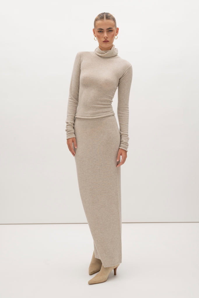 Oatmeal Olivia Turtleneck Delicately soft and consciously crafted, it's the perfect foundation for any outfit.-Classic turtleneck silhouette -Extra-long neck trim for versatile styling (folding and stacking)-Long sleeves designed for slight stacking at the wrist-Rolled wrist and bottom hem 🐑 Made with Good Cashmere Standard® wool to support the welfare of cashmere goats We recommend ordering your usual size.Styled with the Ava Skirt