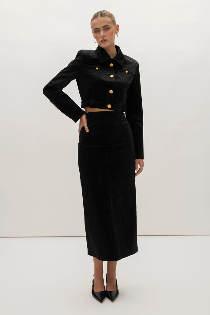 Black Ostrich Meredith Skirt A fresh take on the classic pencil skirt, this style is crafted with vegan ostrich- embossed leather. It features belt loops for effortless styling and is finished with ROARI's signature gold knot button at left hip. Fully lined. We recommend ordering your usual size.Styled with the Meredith Jacket