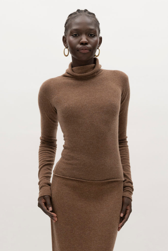Brown Olivia Turtleneck Delicately soft and consciously crafted, it's the perfect foundation for any outfit.-Classic turtleneck silhouette -Extra-long neck trim for versatile styling (folding and stacking)-Long sleeves designed for slight stacking at the wrist-Rolled wrist and bottom hem 🐑 Made with Good Cashmere Standard® wool to support the welfare of cashmere goats We recommend ordering your usual size.Styled with the Ava Skirt