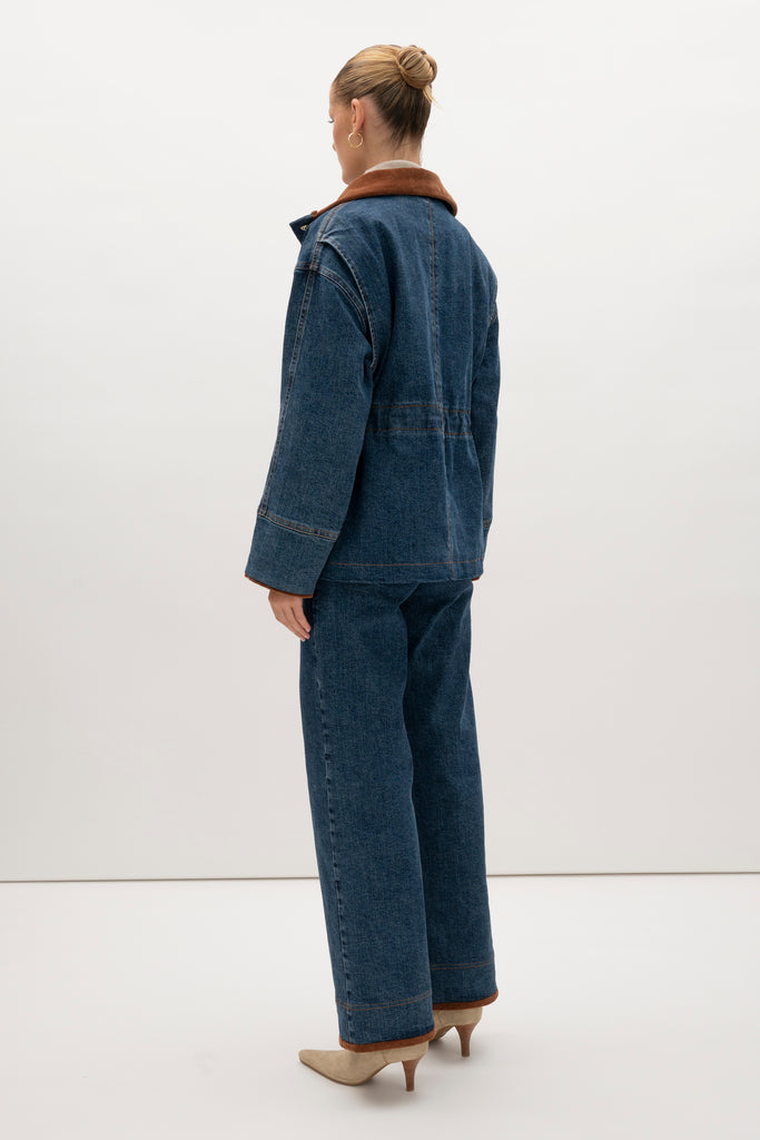 Medium Indigo Torrey Jacket A corduroy collar and gold buttons elevate this classic silhouette, while a drawcord waist lets you personalize the fit. Perfect for layering. -Premium Japanese denim-Cinched-waist jacket-Corduroy-faced collar-Funnel neck-Drawcord tunnel at waist-Welt pockets at front-Self-fabric placket with gold knot buttons-Corduroy faced cuff for option to roll-Flannel lined interior♻️ Environmentally conscious: Made with up-cycled Japanese denim that is produced with reduced CO2 emissions and water-conserving processes. We recommend ordering your usual size.Styled with the Torrey Jean & Olivia Turtleneck  