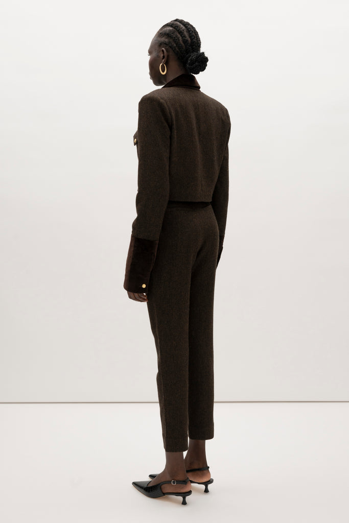 Brown Herringbone Raymond Trouser Expertly tailored in a silhouette that echoes the collection's blend of classic tailoring and modern details. -Straight leg ankle length trouser-Smooth velvet combo waistband-Double-pleated front-Slant front pockets-Self-doubled belt loops-Zip fly with hook and bar closure-Faux welt back pockets-Fully lined for superior comfort and drape 🐑 Crafted with Merino wool certified by the Wool Integrity Programme, ensuring farms adhere to the Five Freedoms of animal welfare. We recommend ordering your usual size.Styled with the Camilo Jacket & Zoey Tank