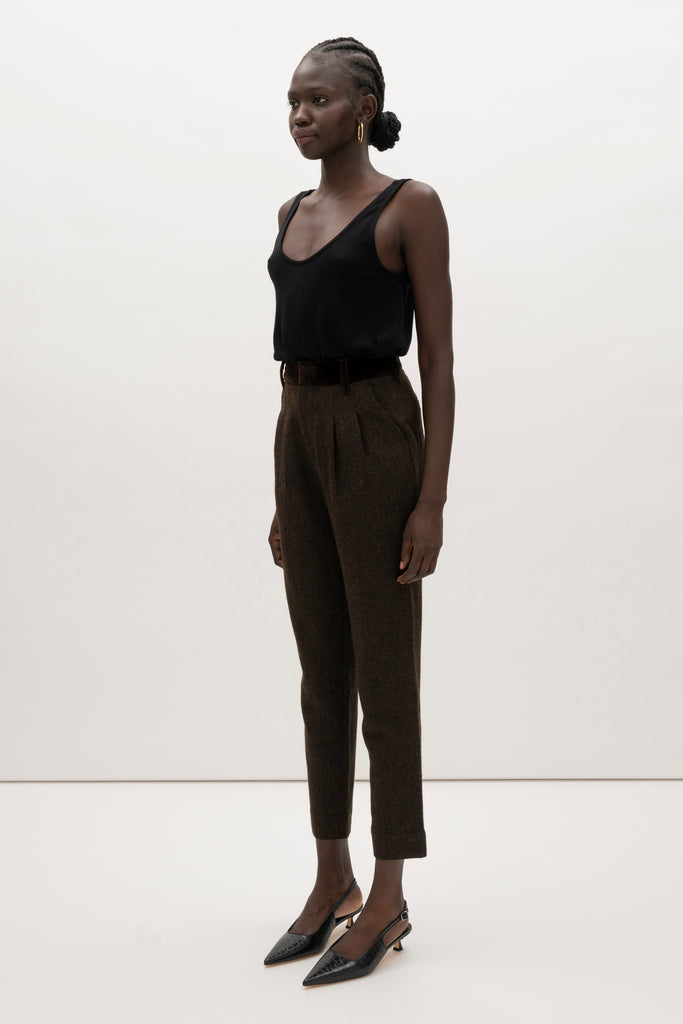 Brown Herringbone Raymond Trouser Expertly tailored in a silhouette that echoes the collection's blend of classic tailoring and modern details. -Straight leg ankle length trouser-Smooth velvet combo waistband-Double-pleated front-Slant front pockets-Self-doubled belt loops-Zip fly with hook and bar closure-Faux welt back pockets-Fully lined for superior comfort and drape 🐑 Crafted with Merino wool certified by the Wool Integrity Programme, ensuring farms adhere to the Five Freedoms of animal welfare. We recommend ordering your usual size.Styled with the Camilo Jacket & Zoey Tank