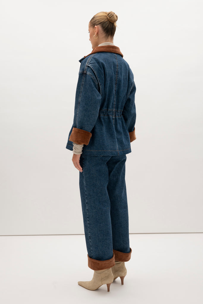 Medium Indigo Torrey Jacket A corduroy collar and gold buttons elevate this classic silhouette, while a drawcord waist lets you personalize the fit. Perfect for layering. -Premium Japanese denim-Cinched-waist jacket-Corduroy-faced collar-Funnel neck-Drawcord tunnel at waist-Welt pockets at front-Self-fabric placket with gold knot buttons-Corduroy faced cuff for option to roll-Flannel lined interior♻️ Environmentally conscious: Made with up-cycled Japanese denim that is produced with reduced CO2 emissions and water-conserving processes. We recommend ordering your usual size.Styled with the Torrey Jean & Olivia Turtleneck  