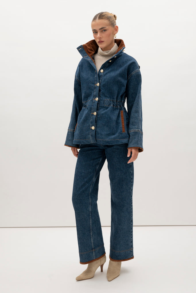 Medium Indigo Torrey Jacket A corduroy collar and gold buttons elevate this classic silhouette, while a drawcord waist lets you personalize the fit. Perfect for layering. -Premium Japanese denim-Cinched-waist jacket-Corduroy-faced collar-Funnel neck-Drawcord tunnel at waist-Welt pockets at front-Self-fabric placket with gold knot buttons-Corduroy faced cuff for option to roll-Flannel lined interior♻️ Environmentally conscious: Made with up-cycled Japanese denim that is produced with reduced CO2 emissions and water-conserving processes. We recommend ordering your usual size.Styled with the Torrey Jean & Olivia Turtleneck  