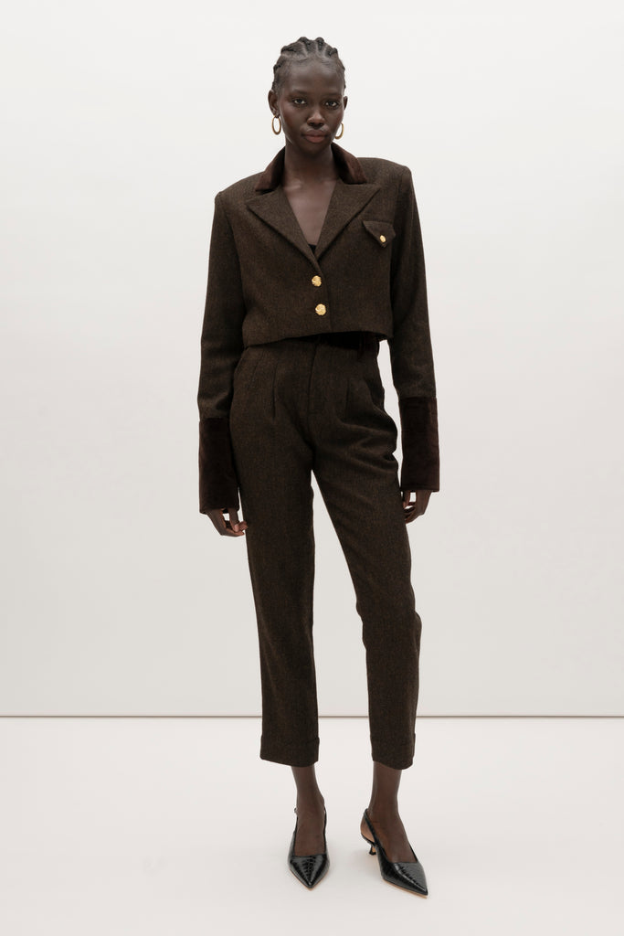 Brown Herringbone Raymond Trouser Expertly tailored in a silhouette that echoes the collection's blend of classic tailoring and modern details. -Straight leg ankle length trouser-Smooth velvet combo waistband-Double-pleated front-Slant front pockets-Self-doubled belt loops-Zip fly with hook and bar closure-Faux welt back pockets-Fully lined for superior comfort and drape 🐑 Crafted with Merino wool certified by the Wool Integrity Programme, ensuring farms adhere to the Five Freedoms of animal welfare. We recommend ordering your usual size.Styled with the Camilo Jacket & Zoey Tank
