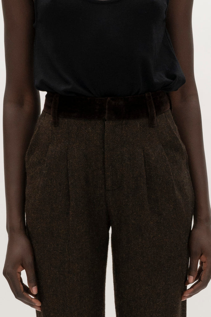 Brown Herringbone Raymond Trouser Expertly tailored in a silhouette that echoes the collection's blend of classic tailoring and modern details. -Straight leg ankle length trouser-Smooth velvet combo waistband-Double-pleated front-Slant front pockets-Self-doubled belt loops-Zip fly with hook and bar closure-Faux welt back pockets-Fully lined for superior comfort and drape 🐑 Crafted with Merino wool certified by the Wool Integrity Programme, ensuring farms adhere to the Five Freedoms of animal welfare. We recommend ordering your usual size.Styled with the Camilo Jacket & Zoey Tank