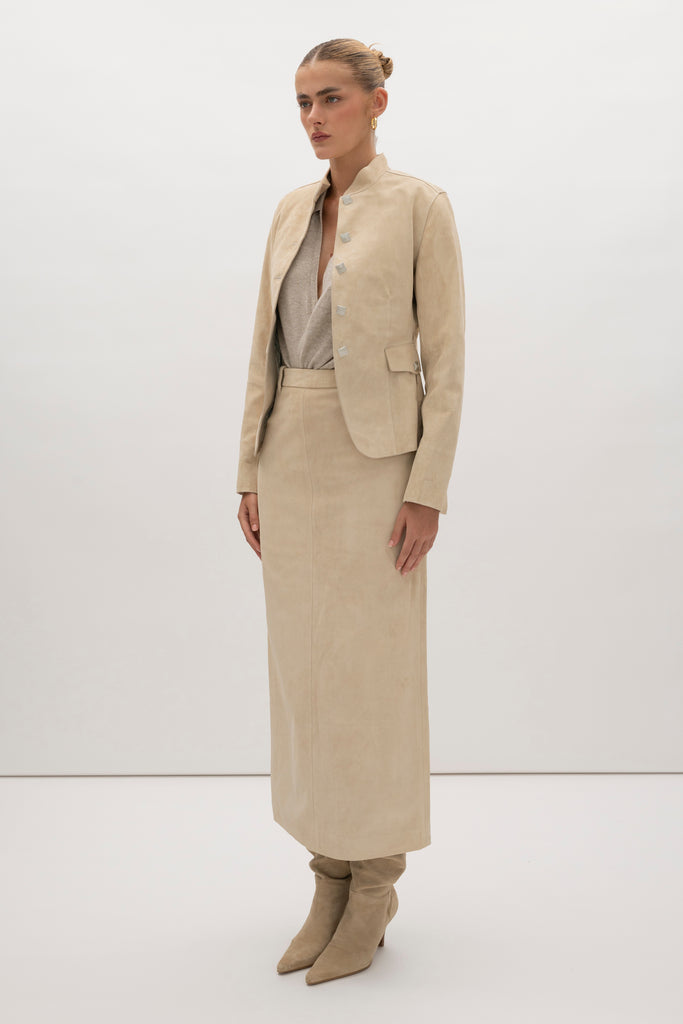 Sand Hyde Jacket -Structured vintage inspired jacket with mandarin collar-Princess seams contour the bodice and waist -100% calf leather (suede) -Ornate front button hardware with interior stay buttons for durability-Hidden zipper pockets integrated into front princess seams-Buttoned pocket flaps for visual detail (non-functional flap; real pocket hidden beneath)-Clean-finished hem, sleeve, and collar with subtle edge stitch detailing-Hidden interior chest pocket with zipper closure-Vents at back of sleeves-Fully linedWe recommend ordering your usual size.Styled with the Meredith Skirt
