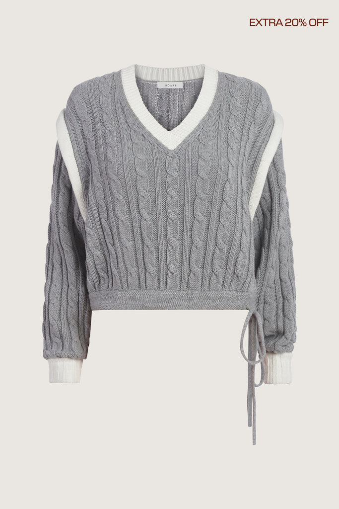  Isabel Sweater Made with 100% cotton yarn, this convertible cable knit sweater features hidden snaps for the option to remove the sleeves. Knit draw cord at waist for choice to cinch or neatly tuck into your favorite jeans. A quintessential seasonless piece.*The top left and right of the removable sleeves will have either a red or white small sewn on marker, indicating which sleeve goes where for ease when placing back on.Ingryd is 5'10