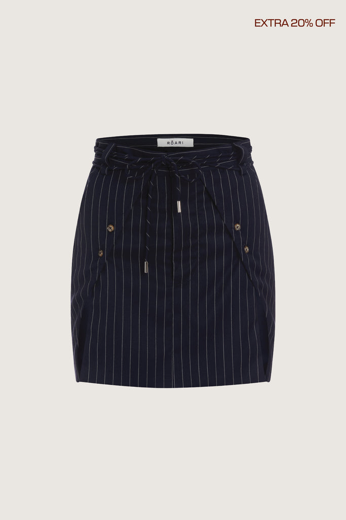Navy Pinstripe Ronnie Skirt Paneled skirt featuring a self-fabric waist tie tunneled through two rows of belt loops. Double front vents are secured by horn buttons. Slightly lengthened back for added coverage.Fits true to sizeStyle with The Ronnie Blazer | The Ronnie Corset*FINAL SALE. Please reference our return & exchange policy here. Extra 20% off auto-applied in cart.