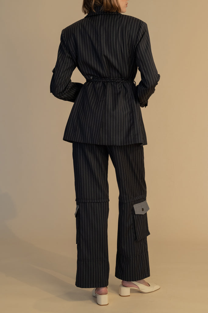 Navy Pinstripe Ronnie Blazer Oversized 90's inspired blazer featuring a fixed self-fabric waist tie, cargo pocket detail on left sleeve, two standard flap pockets at hips, and custom selected horn buttons.