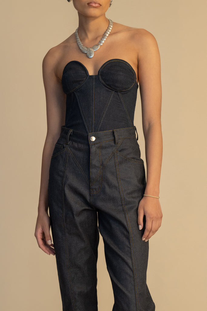 Raw Indigo Chloe Corset This strapless corset features a fitted denim bodice with contoured boning, moldable wiring at cups, and shirred back panels to ensure a snug yet flexible fit. Slightly cropped with a v-front silhouette.