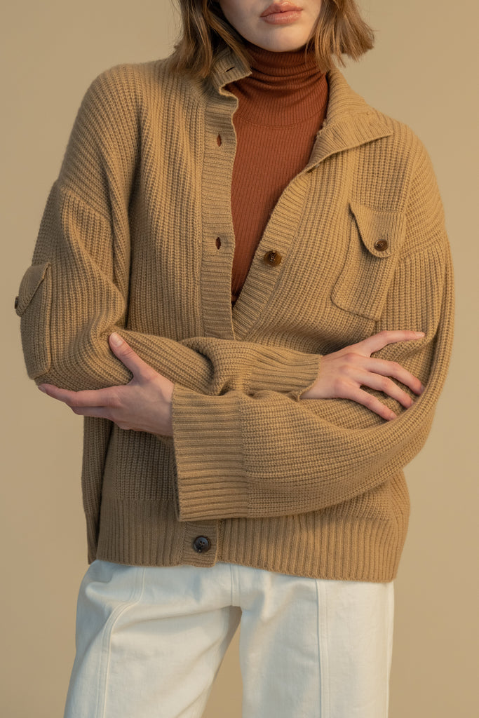 Creme Brulee GRAHAM CARIDGAN This 100% royal cashmere cardigan features an oversized silhouette that hits below the hip, perfect for layering. Features horn buttons along with pockets at chest and right sleeve. Can be worn open or buttoned up as a turtleneck.