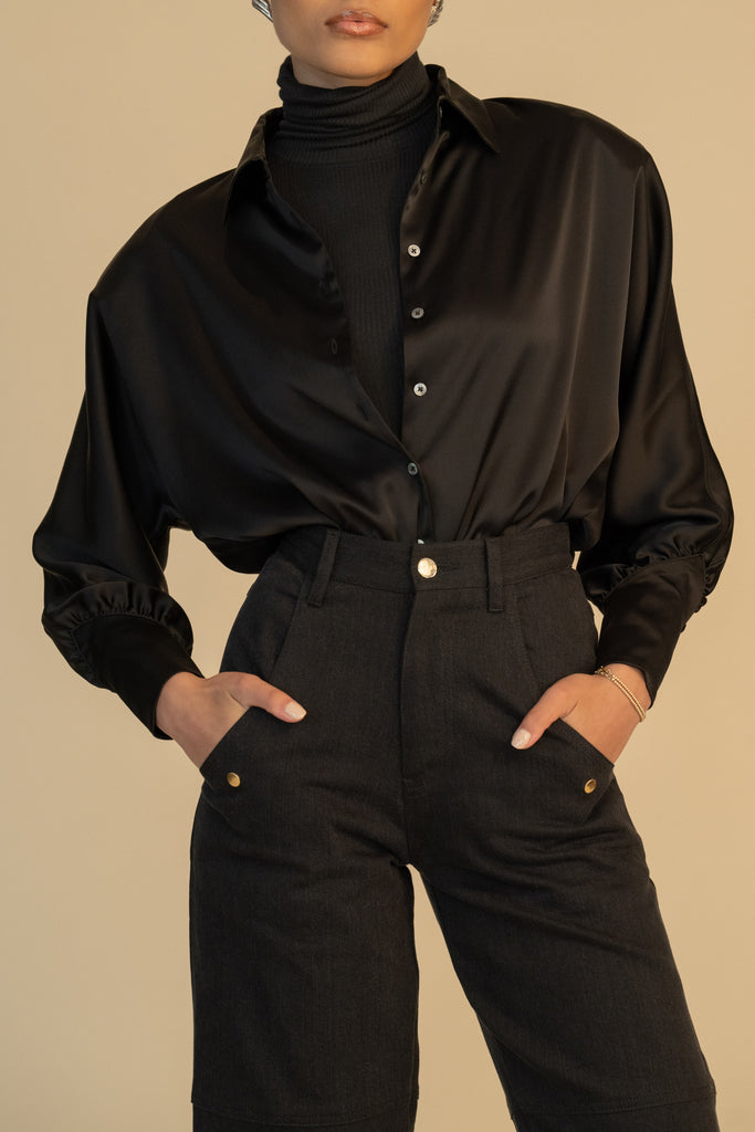 Black Marna Shirt A silky button down featuring blouson sleeves. Composed of wrinkle resistant vegan silk, this top includes mother of pearl buttons, concealed zippers at wrists, and removable shoulder pads.  