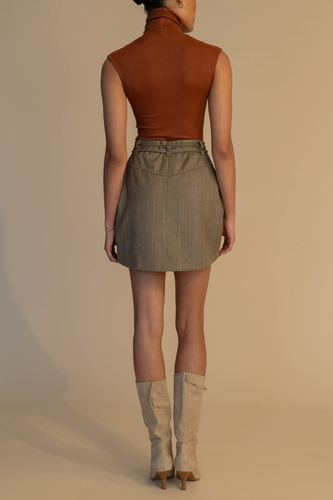 Camel Herringbone Pre-Order | RONNIE SKIRT *SHIPS END OF NOVEMBER. Please note that any order containing a pre-order item/s will be shipped when pre-order item/s become available. We suggest placing two orders if you'd like to receive now available items quicker. Paneled skirt featuring a self-fabric waist tie tunneled through two rows of belt loops. Double front vents are secured by horn buttons. Slightly lengthened back for added coverage. 
