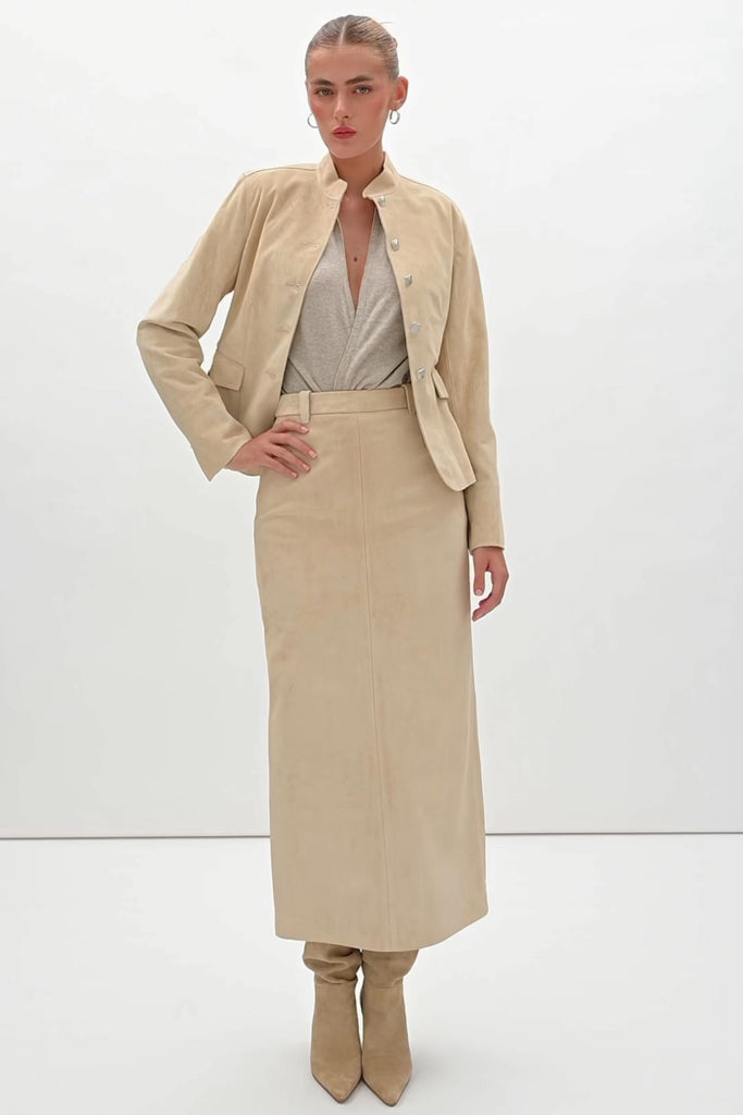 Sand Hyde Jacket -Structured vintage inspired jacket with mandarin collar-Princess seams contour the bodice and waist -100% calf leather (suede) -Ornate front button hardware with interior stay buttons for durability-Hidden zipper pockets integrated into front princess seams-Buttoned pocket flaps for visual detail (non-functional flap; real pocket hidden beneath)-Clean-finished hem, sleeve, and collar with subtle edge stitch detailing-Hidden interior chest pocket with zipper closure-Vents at back of sleeves-Fully linedWe recommend ordering your usual size.Styled with the Meredith Skirt