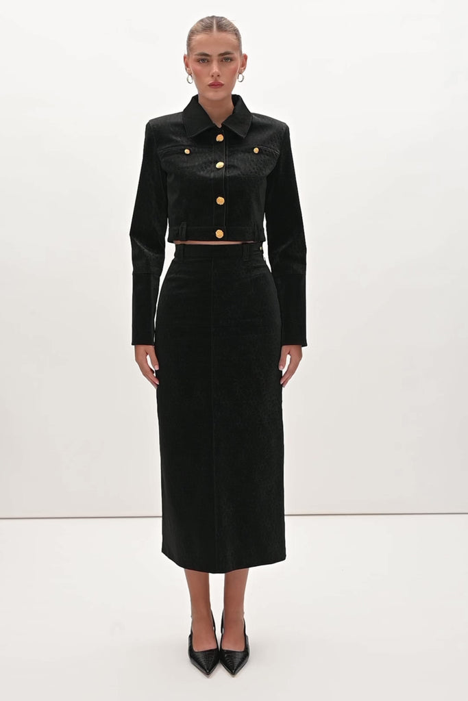Black Ostrich Meredith Skirt A fresh take on the classic pencil skirt, this style is crafted with vegan ostrich- embossed leather. It features belt loops for effortless styling and is finished with ROARI's signature gold knot button at left hip. Fully lined. We recommend ordering your usual size.Styled with the Meredith Jacket