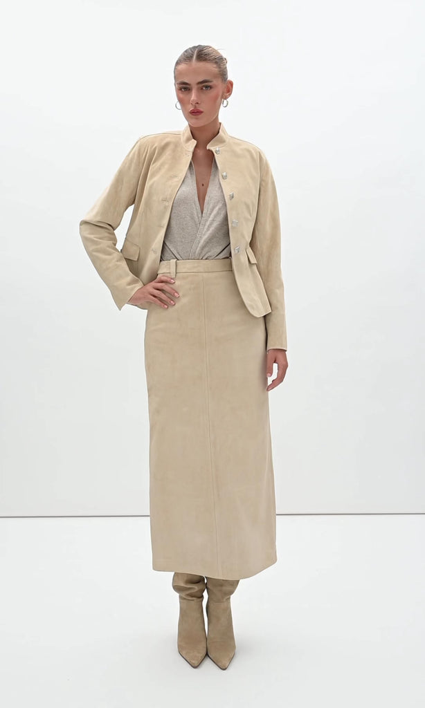Sand Hyde Jacket -Structured vintage inspired jacket with mandarin collar-Princess seams contour the bodice and waist -100% calf leather (suede) -Ornate front button hardware with interior stay buttons for durability-Hidden zipper pockets integrated into front princess seams-Buttoned pocket flaps for visual detail (non-functional flap; real pocket hidden beneath)-Clean-finished hem, sleeve, and collar with subtle edge stitch detailing-Hidden interior chest pocket with zipper closure-Vents at back of sleeves-Fully linedWe recommend ordering your usual size.Styled with the Meredith Skirt