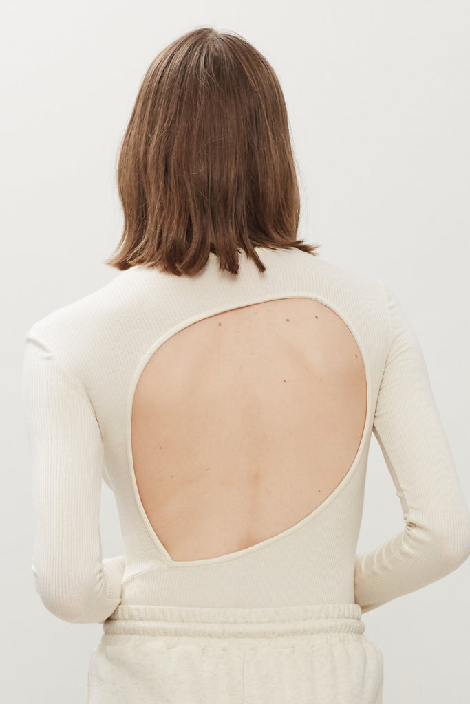 Bone Baby Bodysuit This buttery soft long sleeved bodysuit features a sleek silhouette with a crew neckline and an asymmetrical bold back cutout. *Please reference our return & exchange policy for Bodysuits.