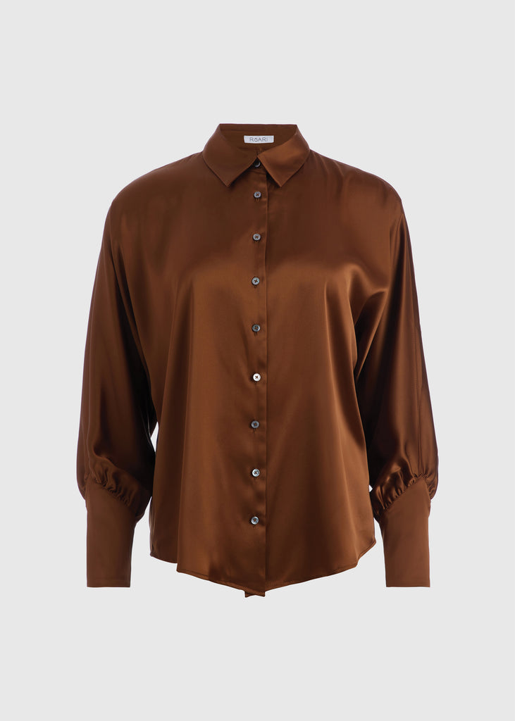 Cinnamon Marna Shirt A silky button down featuring blouson sleeves. Composed of wrinkle resistant vegan silk, this top includes mother of pearl buttons, concealed zippers at wrists, and removable shoulder pads.  