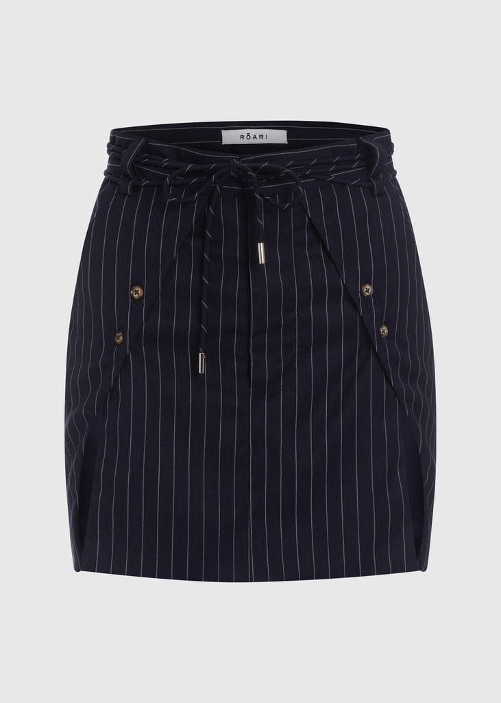 Navy Pinstripe Ronnie Skirt Paneled skirt featuring a self-fabric waist tie tunneled through two rows of belt loops. Double front vents are secured by horn buttons. Slightly lengthened back for added coverage. 