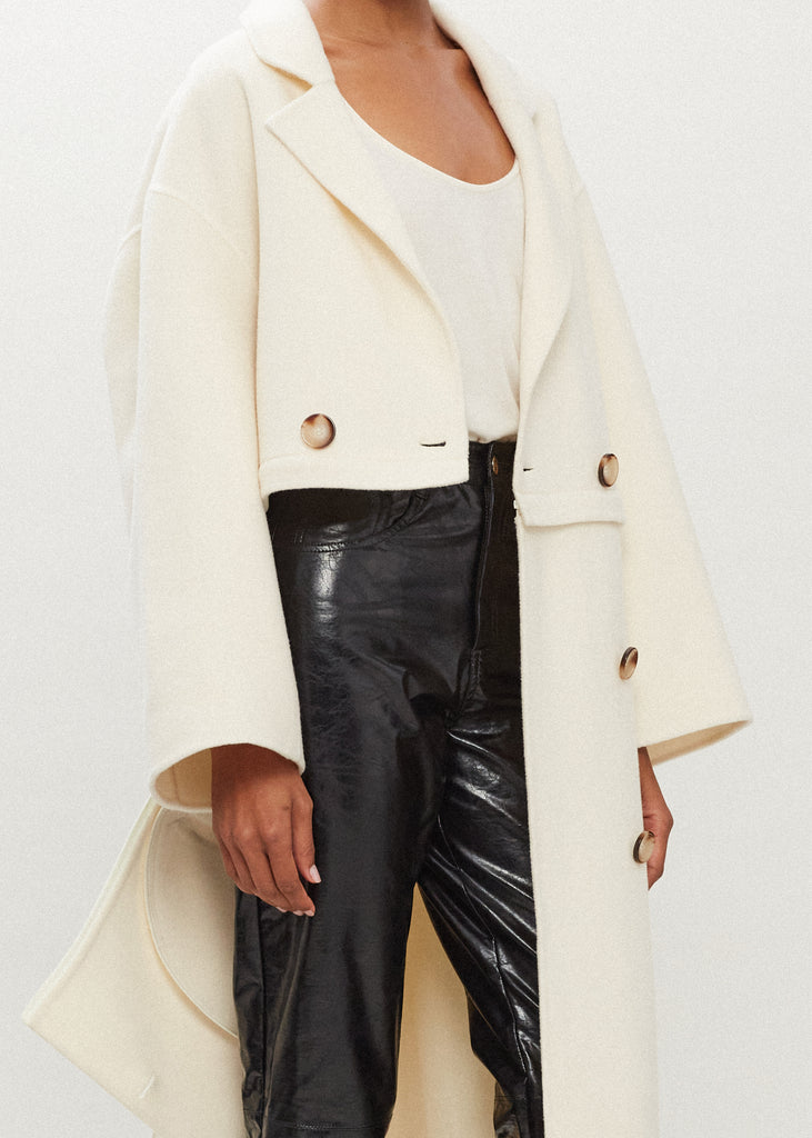 Bone Evelyn Coat This convertible coat features a low double breasted front with horn buttons and dropped shoulders. Purposefully designed oversized to allow for comfortable layering. Zipper above welt side pockets allows to double as a cropped jacket. 