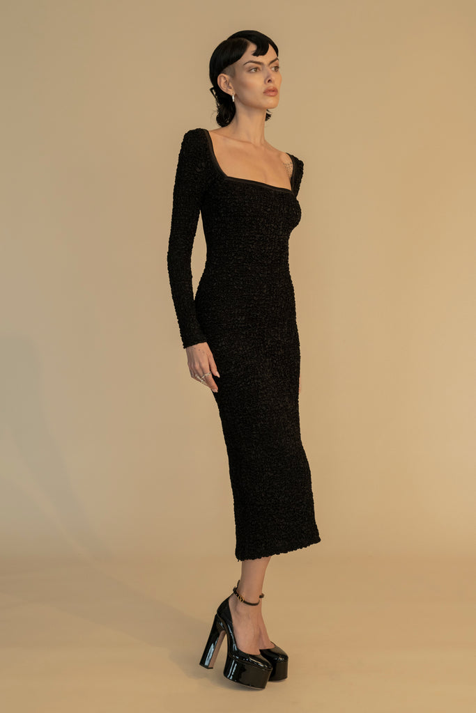 Black YELENA DRESS A midi length smocked dress with square neckline and backless gold chain detailing. Vented side zips and concealed zip closure at back. Hand made in India. 