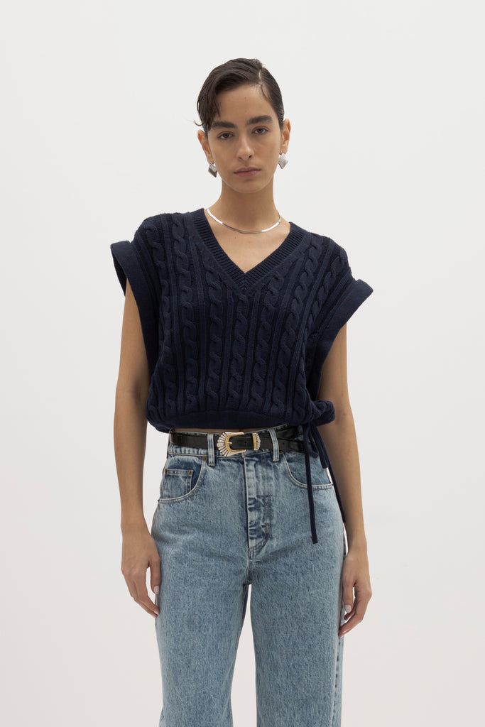 Navy Isabel Sweater Made with 100% cotton yarn, this convertible cable knit sweater features hidden snaps for the option to remove the sleeves. Knit draw cord at waist for choice to cinch or neatly tuck into your favorite jeans. A quintessential seasonless piece.*The top left and right of the removable sleeves will have either a red or white small sewn on marker, indicating which sleeve goes where for ease when placing back on. Ingryd is 5'10