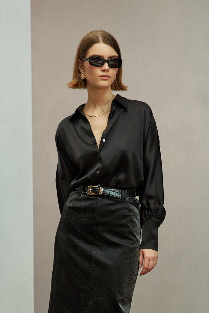 Black Marna Shirt A silky button down featuring blouson sleeves. Composed of wrinkle resistant vegan silk, this top includes mother of pearl buttons, concealed zippers at wrists, and removable shoulder pads. 