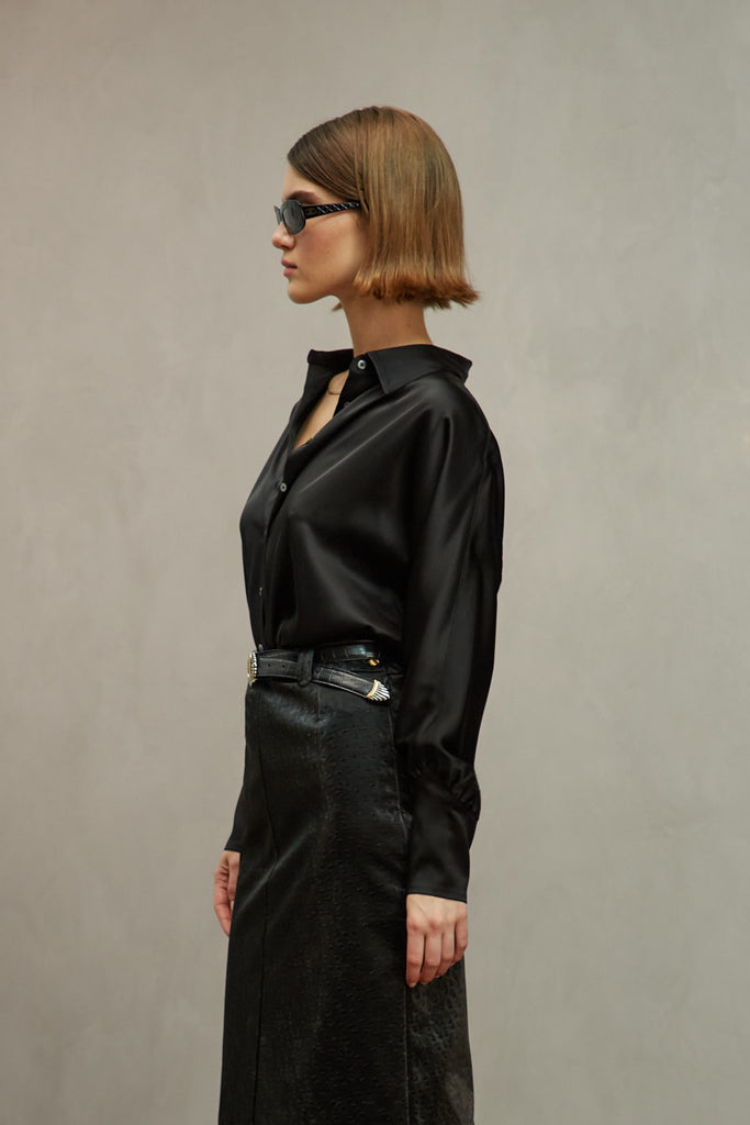 Black Marna Shirt A silky button down featuring blouson sleeves. Composed of wrinkle resistant vegan silk, this top includes mother of pearl buttons, concealed zippers at wrists, and removable shoulder pads. 