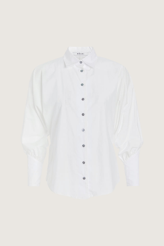 White Marna Poplin Shirt Classic tailored button-up shirt in midweight 100% Supima cotton. Featuring blousoned dolman sleeves with, Mother of Pearl buttons down center front placket, and concelead zippers at wrists with reverse V cut cuff details.Styled with The Sarah Stretch Jean