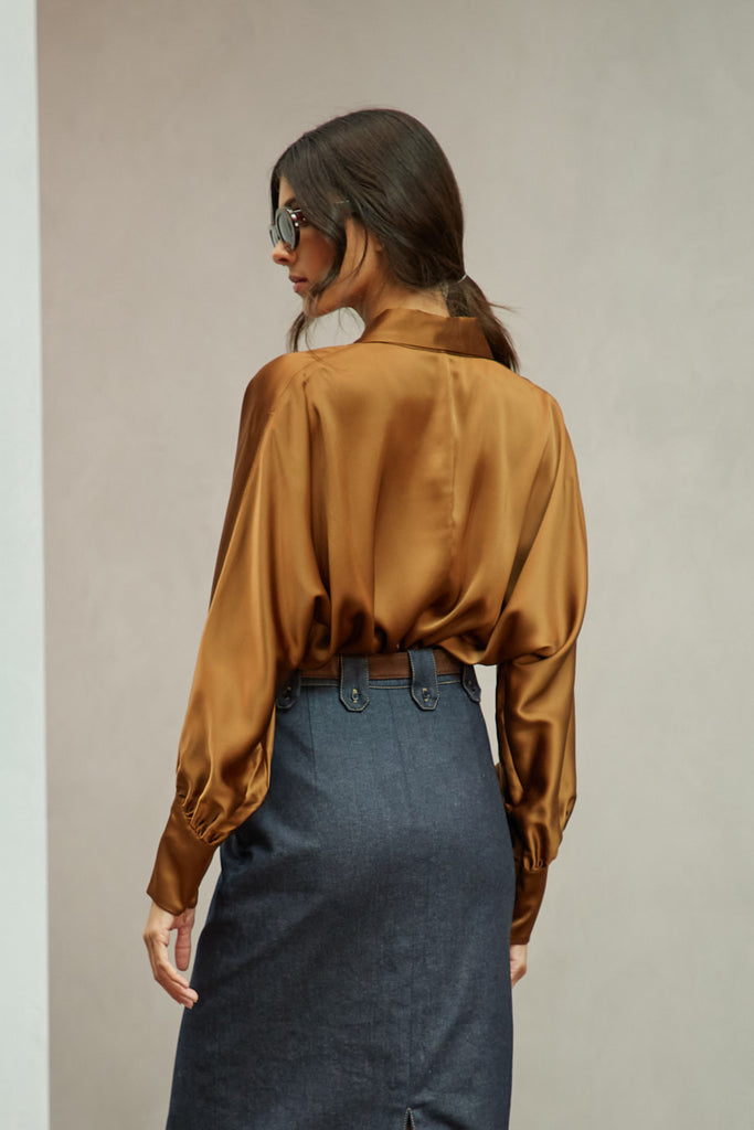 Cinnamon Marna Shirt A silky button down featuring blouson sleeves. Composed of wrinkle resistant vegan silk, this top includes mother of pearl buttons, concealed zippers at wrists, and removable shoulder pads. 