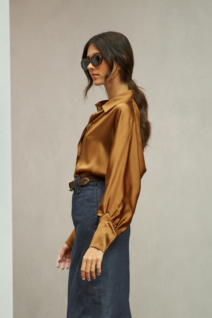 Cinnamon Marna Shirt A silky button down featuring blouson sleeves. Composed of wrinkle resistant vegan silk, this top includes mother of pearl buttons, concealed zippers at wrists, and removable shoulder pads. 