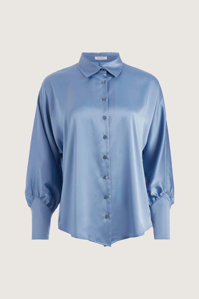 Sky Marna Shirt A silky button down featuring blouson sleeves. Composed of wrinkle resistant vegan silk, this top includes mother of pearl buttons, concealed zippers at wrists, and removable shoulder pads. 