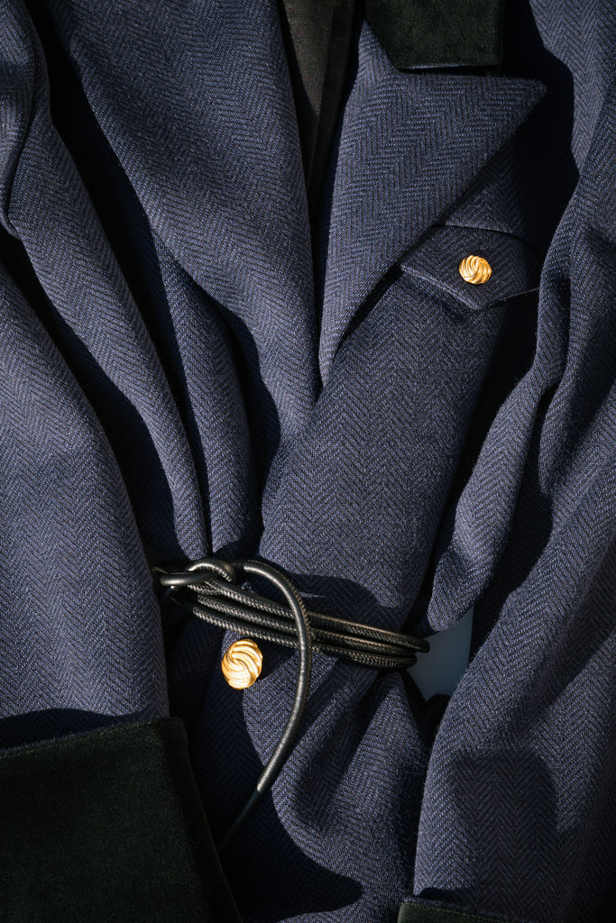 Navy Herringbone Meredith Coat This single breasted Italian wool coat is highlighted with contrasting velvet details at the collar and cuffs, providing multiple styling possibilities. It includes a 100% lambskin wrap belt and features double side vents for enhanced comfort. It is finished with RŌARI's signature gold knot buttons. Fully lined. Styled with The Meredith Trouser | The Meredith Skirt *Please reference our return & exchange policy for Sale & Archived items.