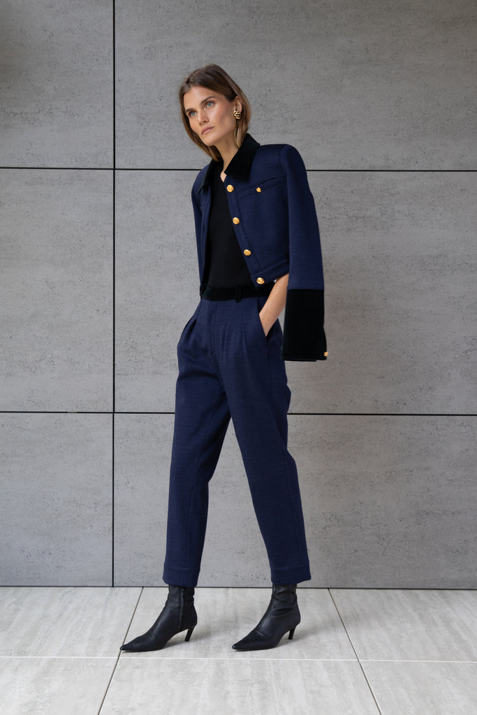 Navy Herringbone Meredith Jacket A fresh take on the classic suit jacket, this cropped style is crafted with fine Italian virgin wool. Detailed contrasting velvet at collar, belt loops, and cuffs. Finished with ROARI's signature gold knot buttons at center front, welt pockets and cuffs. Fully lined.Styled with The Meredith Trouser | The Meredith SkirtAlso available in Black Ostrich *Please reference our return & exchange policy for Sale & Archived items.