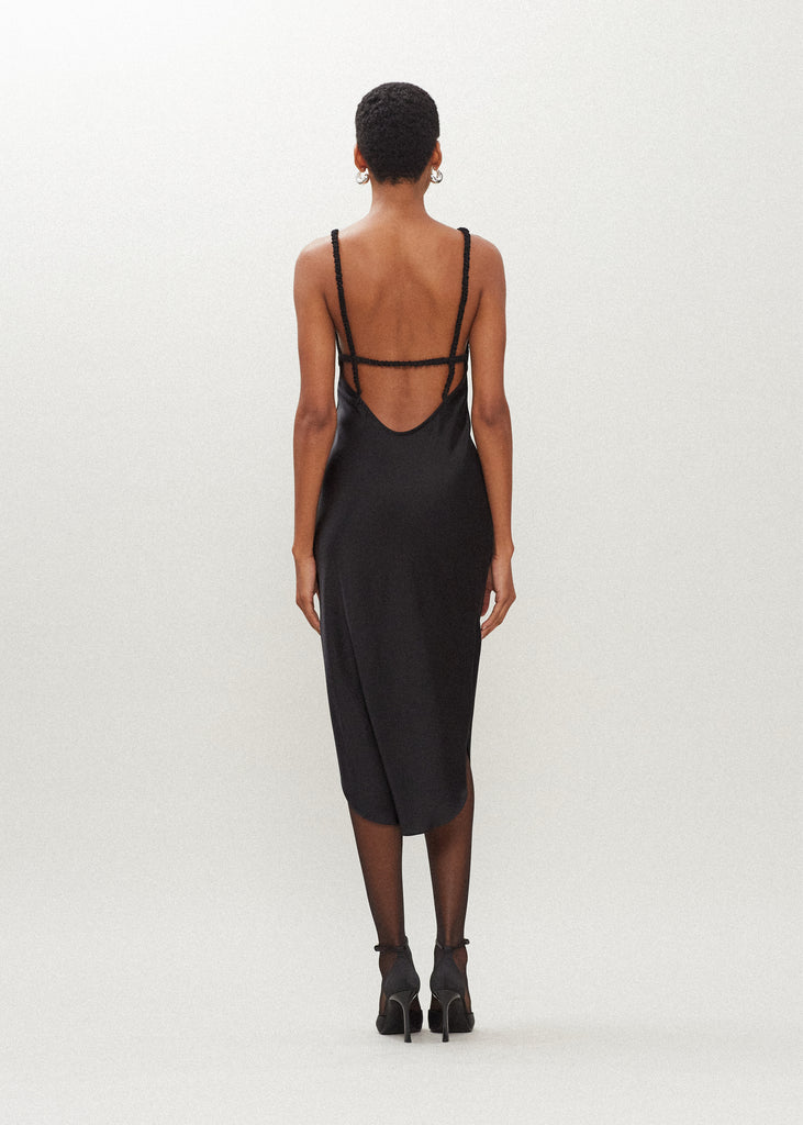 Black Paras Dress The Paras vegan silk midi slip dress features a v-neckline with scalloped trim, bust darts, ruched elastic straps, a low cut open back, and a curved, vented hemline.SALE MERCHANDISE IS EXCHANGE OR STORE CREDIT ONLY