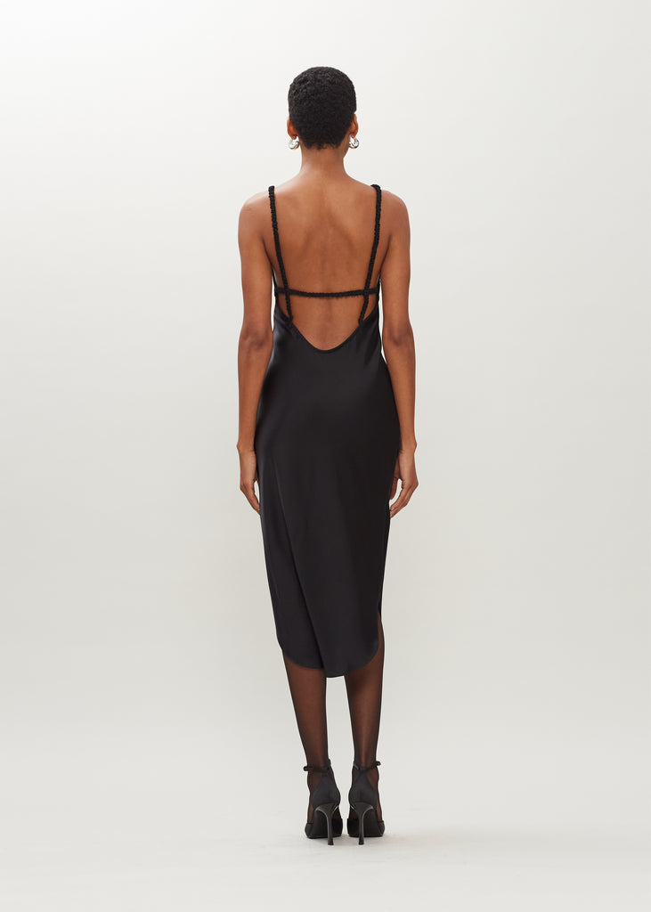 Black Paras Dress The Paras vegan silk midi slip dress features a v-neckline with scalloped trim, bust darts, ruched elastic straps, a low cut open back, and a curved, vented hemline.We recommend ordering your usual size.  *FINAL SALE. Please reference our return & exchange policy here.Extra 20% off auto-applied in cart.