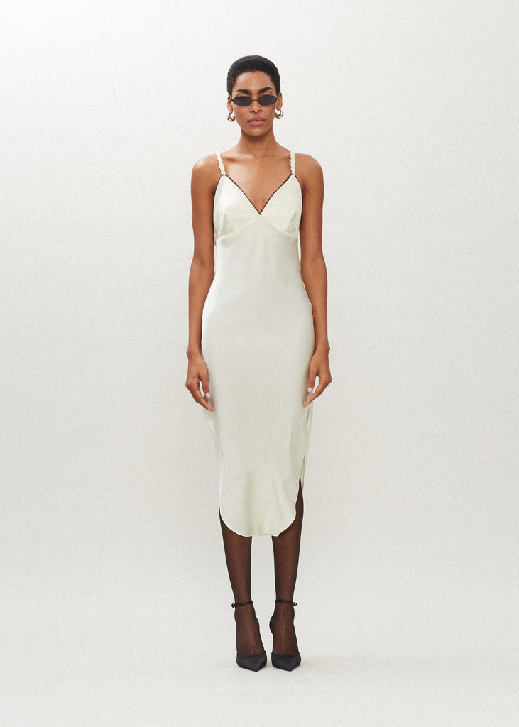 Bone Paras Dress The Paras vegan silk midi slip dress features a v-neckline with scalloped trim, bust darts, ruched elastic straps, a low cut open back, and a curved, vented hemline.*Sale merchandise is exchangeable for size/color or store credit. 