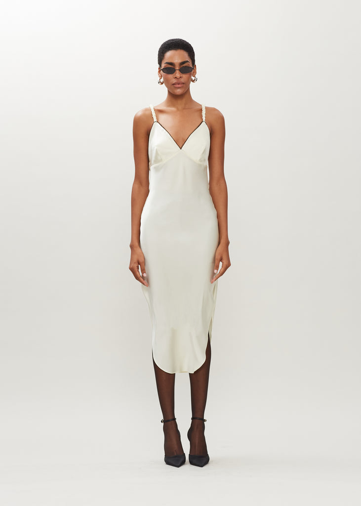 Bone Paras Dress The Paras vegan silk midi slip dress features a v-neckline with scalloped trim, bust darts, ruched elastic straps, a low cut open back, and a curved, vented hemline.We recommend ordering your usual size.  *FINAL SALE. Please reference our return & exchange policy here.Extra 20% off auto-applied in cart.