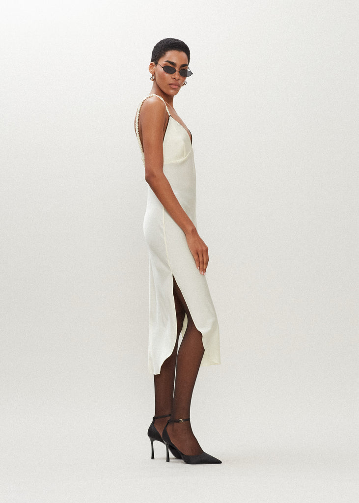 Bone Paras Dress The Paras vegan silk midi slip dress features a v-neckline with scalloped trim, bust darts, ruched elastic straps, a low cut open back, and a curved, vented hemline.*Sale merchandise is exchangeable for size/color or store credit. 