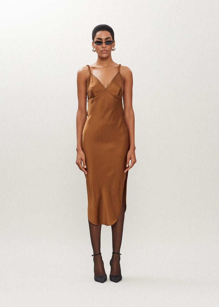 Cinnamon Paras Dress The Paras vegan silk midi slip dress features a v-neckline with scalloped trim, bust darts, ruched elastic straps, a low cut open back, and a curved, vented hemline.SALE MERCHANDISE IS EXCHANGE OR STORE CREDIT ONLY