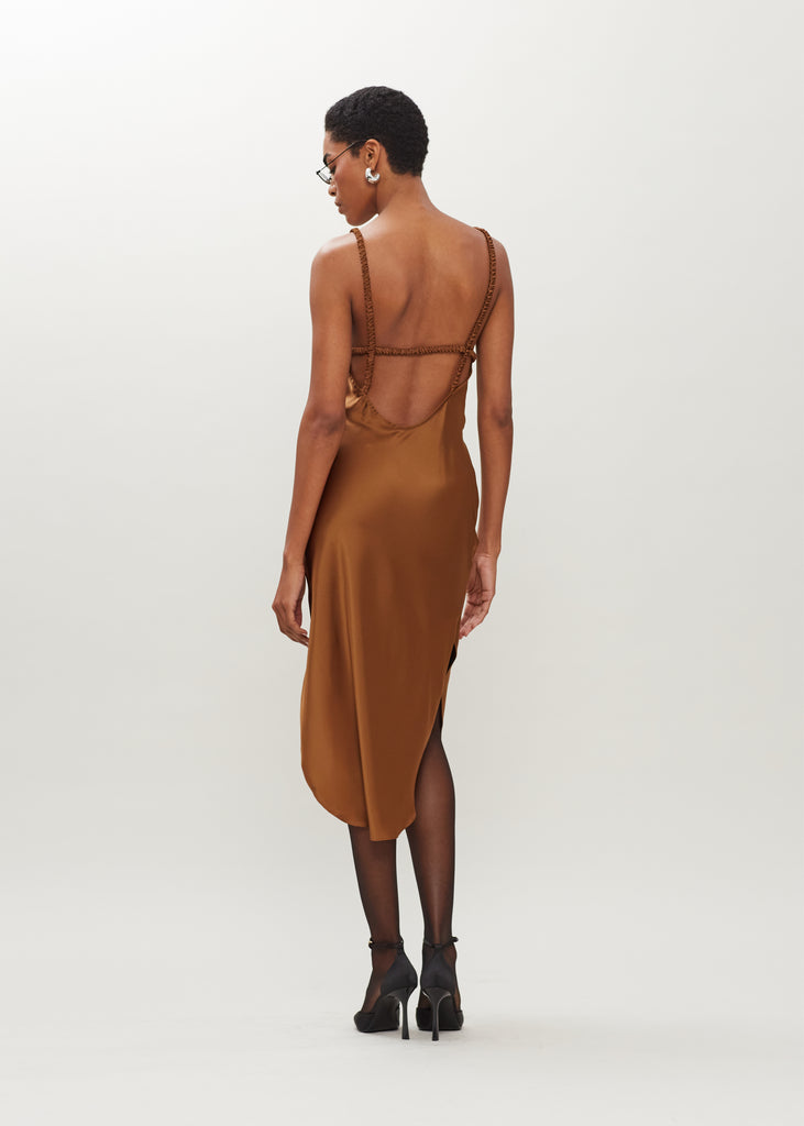 Cinnamon Paras Dress The Paras vegan silk midi slip dress features a v-neckline with scalloped trim, bust darts, ruched elastic straps, a low cut open back, and a curved, vented hemline.We recommend ordering your usual size.  *FINAL SALE. Please reference our return & exchange policy here.Extra 20% off auto-applied in cart.