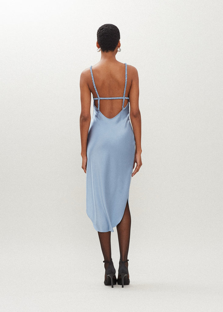 Sky Paras Dress The Paras vegan silk midi slip dress features a v-neckline with scalloped trim, bust darts, ruched elastic straps, a low cut open back, and a curved, vented hemline.SALE MERCHANDISE IS EXCHANGE OR STORE CREDIT ONLY
